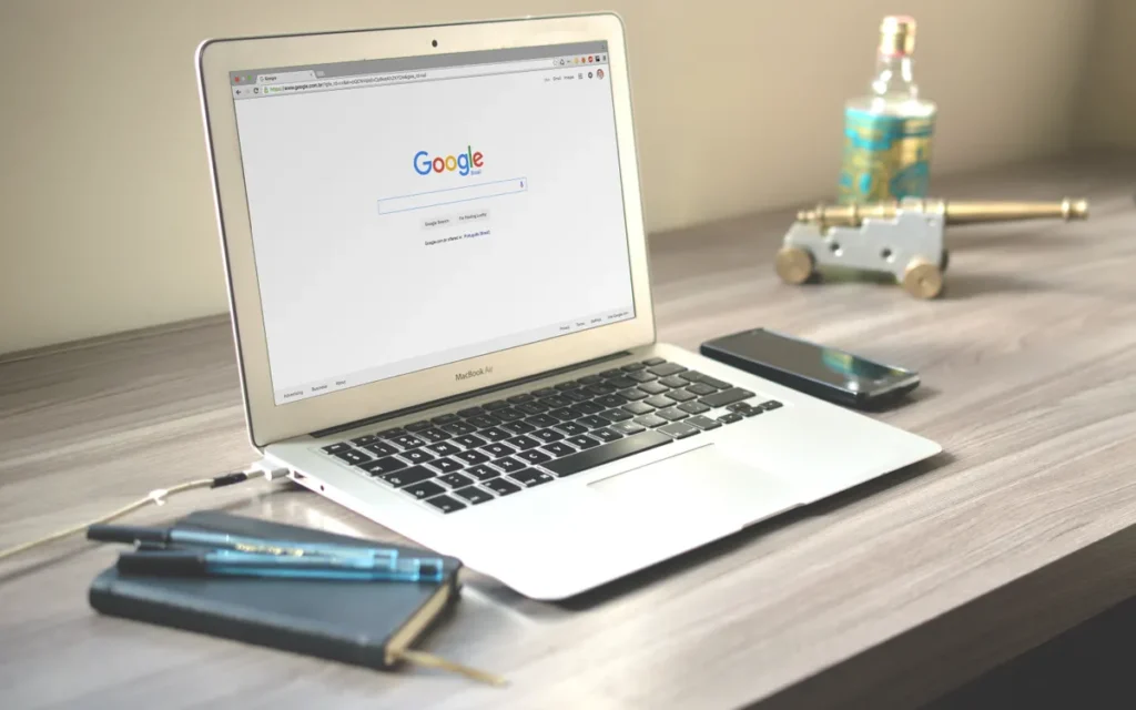 Google aramasını gösteren dizüstü bilgisayarın olduğu düzenli çalışma alanı